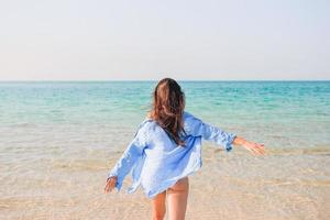 donna posa su il spiaggia godendo estate vacanze guardare a il mare foto