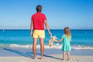 papà con poco bambino Tenere un' felpa giocattolo su esotico spiaggia foto