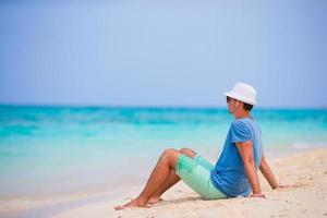 contento giovane uomo godendo il musica su bianca sabbioso spiaggia foto