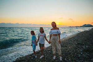 adorabili bambine e giovane madre sulla spiaggia bianca tropicale foto