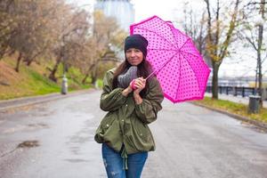 giovane donna a piedi con ombrello nel autunno piovoso giorno foto