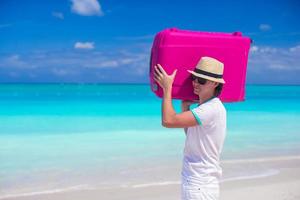 ritratto di un' giovane uomo trasporto il suo bagaglio su il spiaggia foto