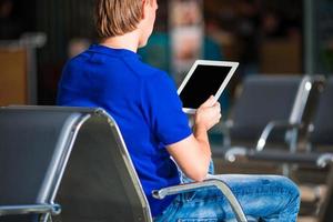 giovane uomo con il computer portatile a il aeroporto mentre in attesa per imbarco foto