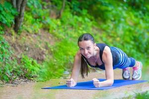 giovane donna sorridente facendo esercizi sportivi all'aperto foto