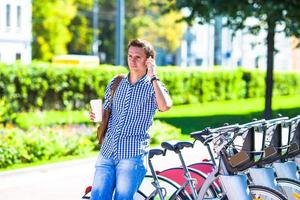 giovane uomo con bicchiere di caffè su bicicletta all'aperto foto