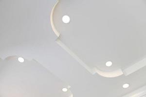 allungare soffitto bianca e complesso forma. soffitto con alogeno macchie lampade e cartongesso costruzione nel vuoto camera nel esposizione sala o Casa. foto