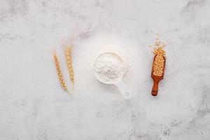 gli ingredienti per l'impasto della pizza fatta in casa con spighe di grano, farina di grano e chicchi di grano allestiti su sfondo bianco di cemento. foto