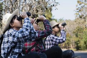 asiatico ragazzi siamo utilizzando binocolo per fare il uccelli' Guardando nel tropicale foresta durante estate campo, idea per apprendimento creature e natura animali e insetti al di fuori il aula. foto