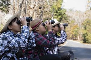 asiatico ragazzi siamo utilizzando binocolo per fare il uccelli' Guardando nel tropicale foresta durante estate campo, idea per apprendimento creature e natura animali e insetti al di fuori il aula. foto