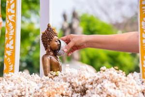 persone versare acqua al di sopra di Budda statue. foto