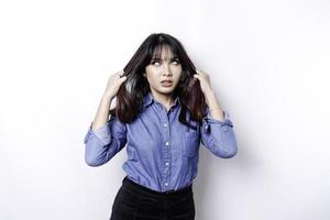 un' ritratto di un asiatico donna indossare un' blu camicia isolato di bianca sfondo sembra depresso foto