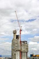 sollevamento gru Lavorando edificio costruzione su luminosa blu cielo e grande nube sfondo. foto