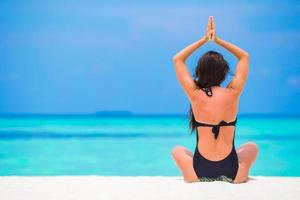 giovane donna seduta nel yoga posizione durante tropicale vacanza foto