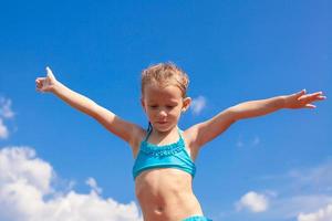 adorabile poco ragazza diffusione sua braccia sfondo di il blu cielo foto