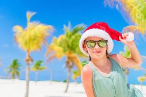 contento poco ragazza nel Santa cappello durante Natale spiaggia vacanza avere un' lotto di divertimento foto