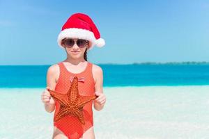 contento poco ragazza nel Santa cappello durante Natale spiaggia vacanza avere un' lotto di divertimento foto