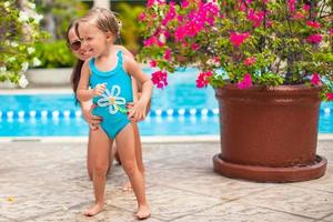 poco contento ragazza con giovane madre avere divertimento vicino piscina foto