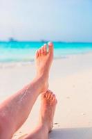 vicino su di femmina piedi su bianca sabbioso spiaggia foto