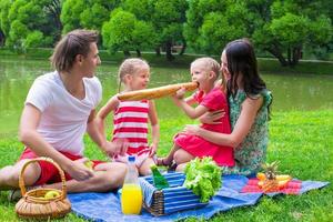 giovane famiglia felice che fa un picnic all'aperto vicino al lago foto