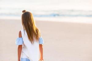 adorabile contento poco ragazza a piedi su bianca spiaggia a tramonto. foto