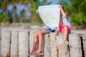 adorabile poco ragazze con grande carta geografica di isola su spiaggia foto