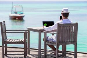 giovane uomo con tavoletta computer su tropicale spiaggia foto