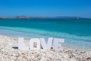 parola amore su tropicale spiaggia sfondo di il turchese mare e blu cielo foto