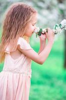 adorabile poco ragazza godendo odore nel un' fioritura ciliegia primavera giardino foto