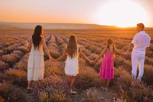 famiglia nel lavanda fiori campo a tramonto nel bianca vestito e cappello foto