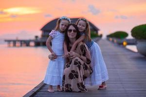 silhouette di giovane madre e Due sua poco ragazze a tramonto foto