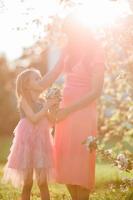 adorabile poco ragazza con giovane madre nel fioritura ciliegia giardino su primavera giorno foto