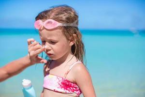 giovane madre l'applicazione crema solare crema su sua di figlia naso foto