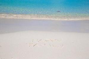contento famiglia scritto su tropicale spiaggia bianca sabbia foto