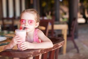 adorabile poco ragazza avendo prima colazione e potabile frutta cocktail foto