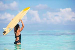 bellissimo surfer donna pronto per fare surf nel turchese mare, su In piedi su pagaia tavola a esotico vacanza foto