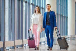 coppia con Bagaglio nel internazionale aeroporto. uomo e donna andando su atterraggio foto