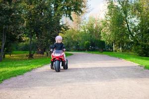 adorabile poco ragazze equitazione su capretto motobike nel il verde parco foto