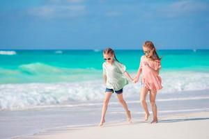 poco ragazze avendo divertimento a tropicale spiaggia giocando insieme a superficiale acqua foto