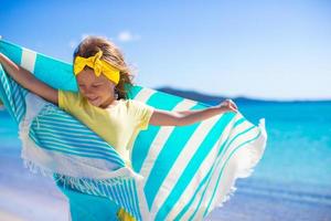 poco adorabile ragazza con spiaggia asciugamano durante tropicale vacanza foto