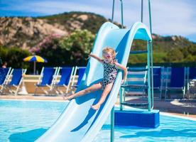 poco ragazza su acqua diapositiva a Parco acquatico su estate vacanza foto