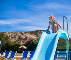 poco ragazza su acqua diapositiva a Parco acquatico su estate vacanza foto