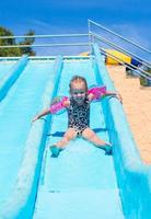 bambino su acqua diapositiva a Parco acquatico durante estate vacanza foto