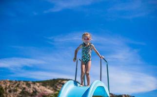 poco ragazza su acqua diapositiva a Parco acquatico su estate vacanza foto