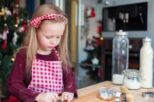 poco carino ragazza cottura al forno Pan di zenzero biscotti per Natale a casa cucina foto