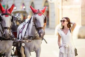 turista ragazza godendo un' passeggiare attraverso vienna e guardare a il bellissimo cavalli nel il carrozza foto