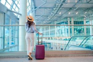 giovane donna nel cappello con Bagaglio nel internazionale aeroporto. foto