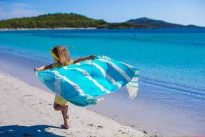 poco carino ragazza avere divertimento con spiaggia asciugamano foto