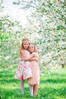 adorabile poco ragazze nel fioritura ciliegia albero giardino su primavera giorno foto