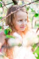 ritratto di poco ragazza nel fioritura Mela albero giardino su primavera giorno foto