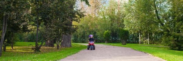 adorabile poco ragazze equitazione su capretto motobike nel il verde parco foto